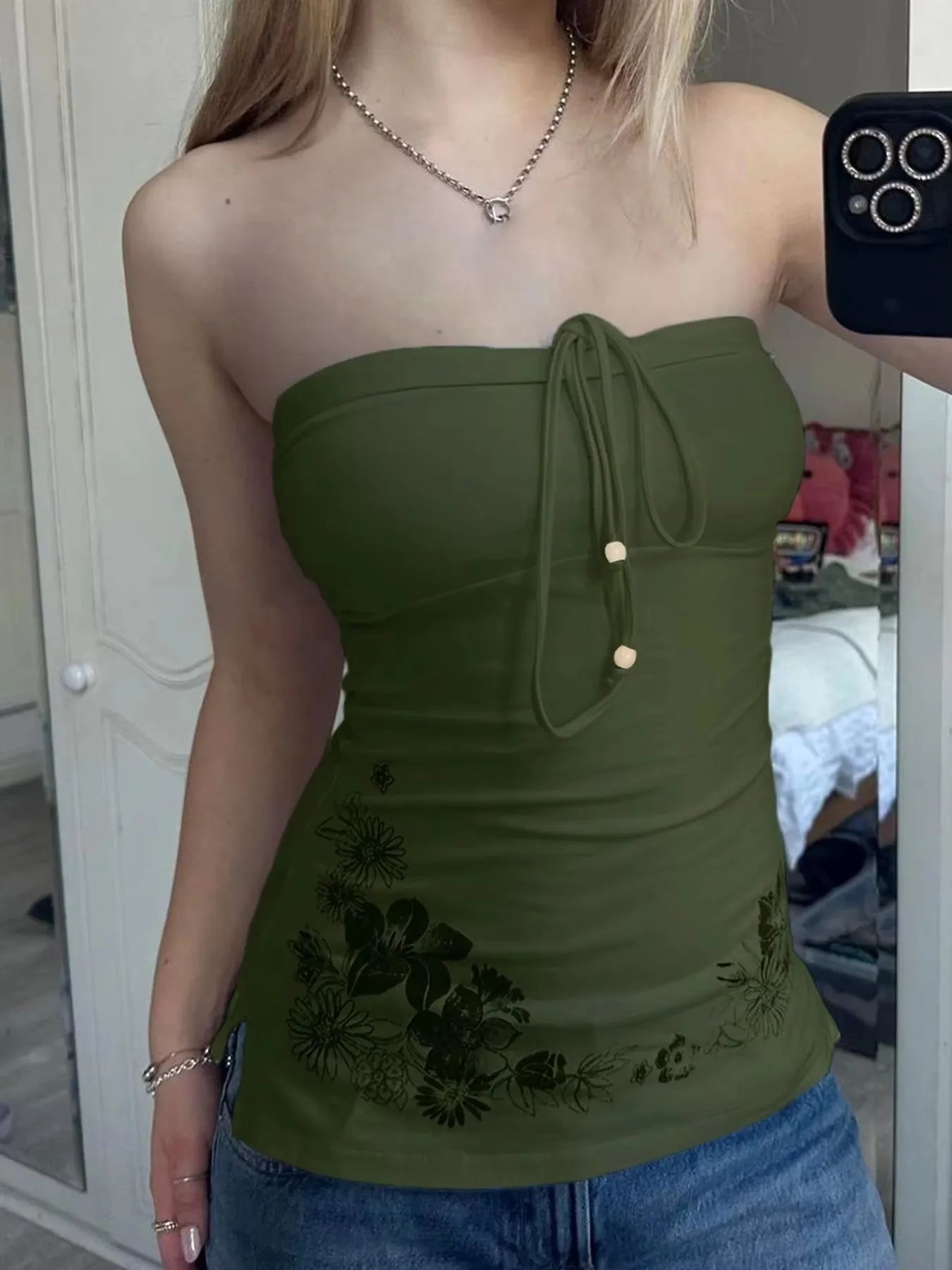 Person wearing a green strapless top with floral details in a casual setting.