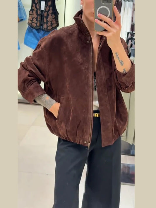 Person wearing a brown jacket taking a mirror selfie in a store.