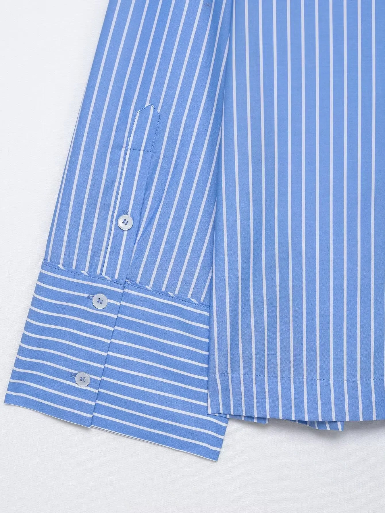 Close-up of a blue and white striped shirt with buttons on a light gray background