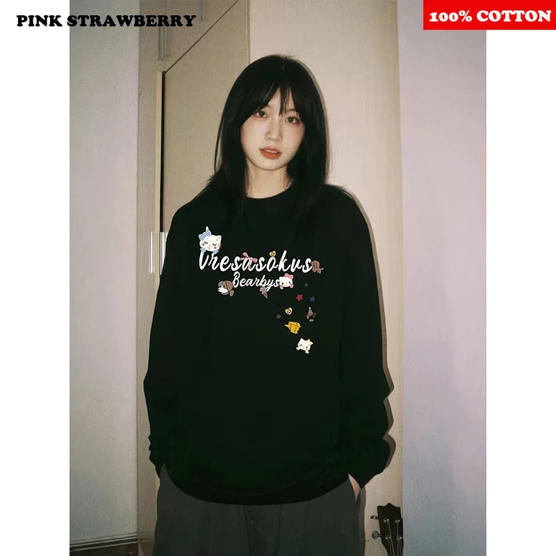 Person wearing a black sweatshirt with graphics and text, standing indoors.