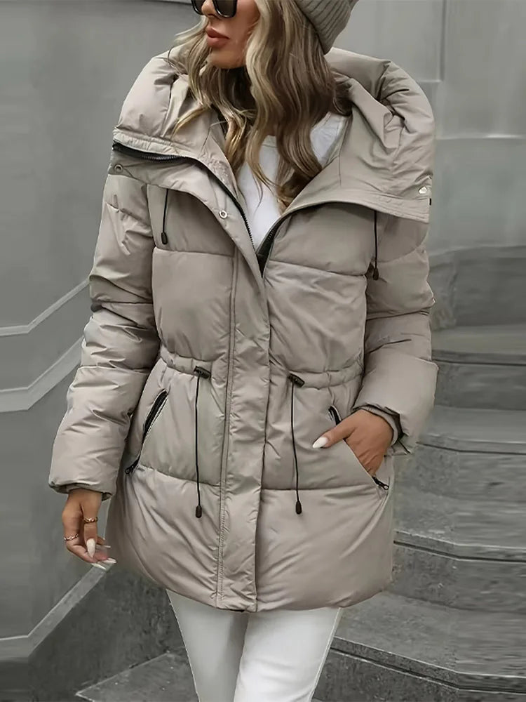Woman wearing a beige puffer jacket on a gray background