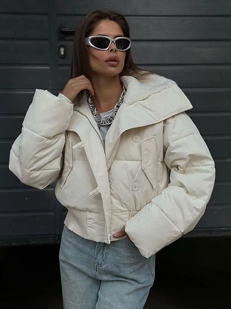 Person wearing a white puffer jacket and sunglasses against a dark background