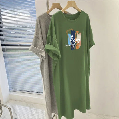 Green dress with a graphic design on a hanger near a window.