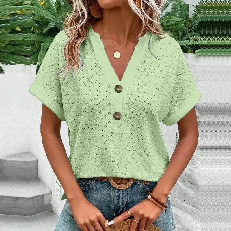 Woman wearing a light green lace top with buttons, standing outdoors.