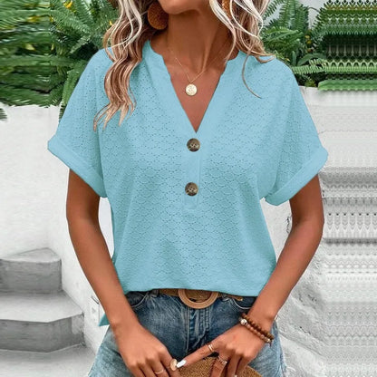 Woman wearing a light blue blouse with buttons and jeans outdoors.