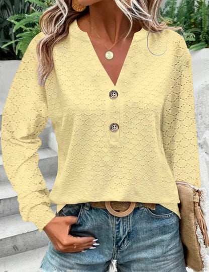 Person wearing a yellow lace top with buttons, standing outdoors.