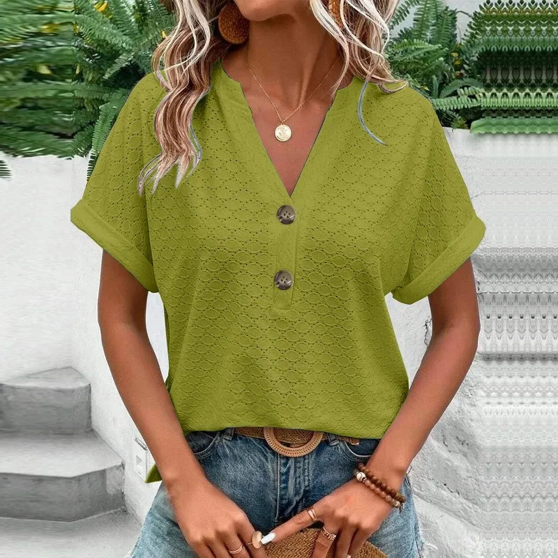 Woman wearing a green blouse with buttons and blue jeans in an outdoor setting.