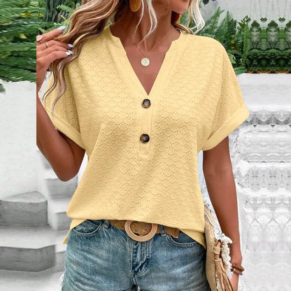Woman wearing a yellow textured top with buttons and blue jeans outdoors.