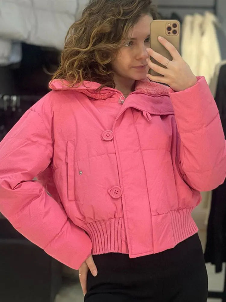 Person wearing a pink puffer jacket taking a mirror selfie.
