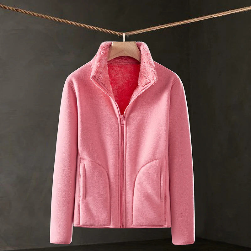 Pink fleece jacket hanging on a line against a dark background