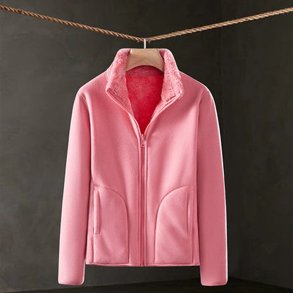 Pink fleece jacket hanging on a line against a dark background