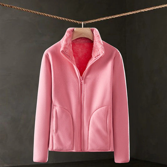 Pink fleece jacket hanging on a line against a dark background