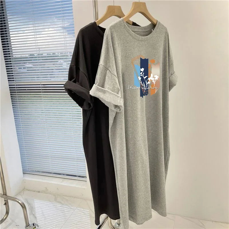 Two long-sleeve shirts, one black and one gray with a graphic design, hanging on wooden hangers against a neutral wall.