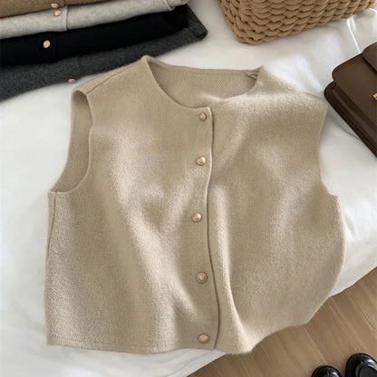 Beige knitted vest with buttons on a white surface