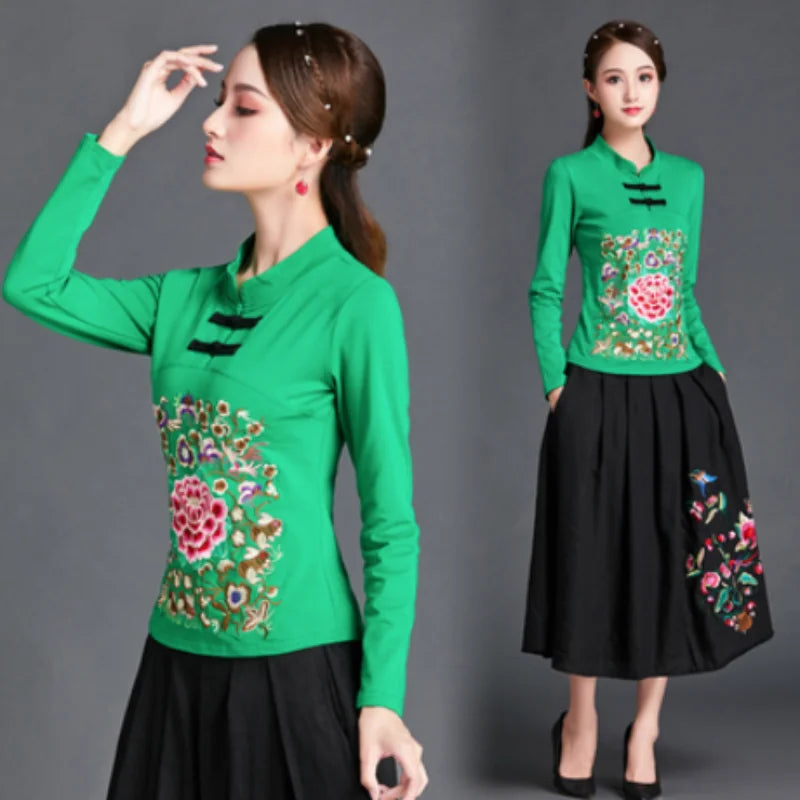 Woman wearing a green top and black skirt with floral embroidery on a gray background