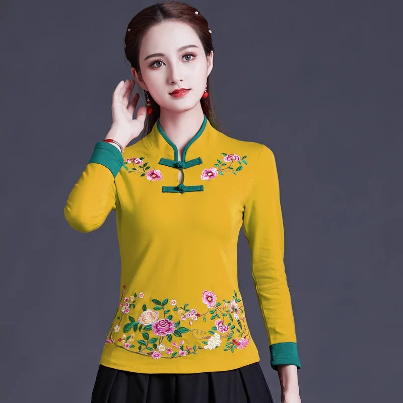 Woman wearing a yellow traditional outfit with floral embroidery on a dark background