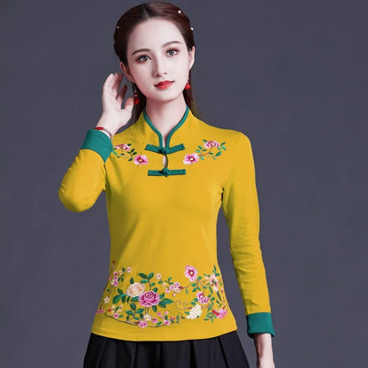 Woman wearing a yellow traditional outfit with floral embroidery on a dark background