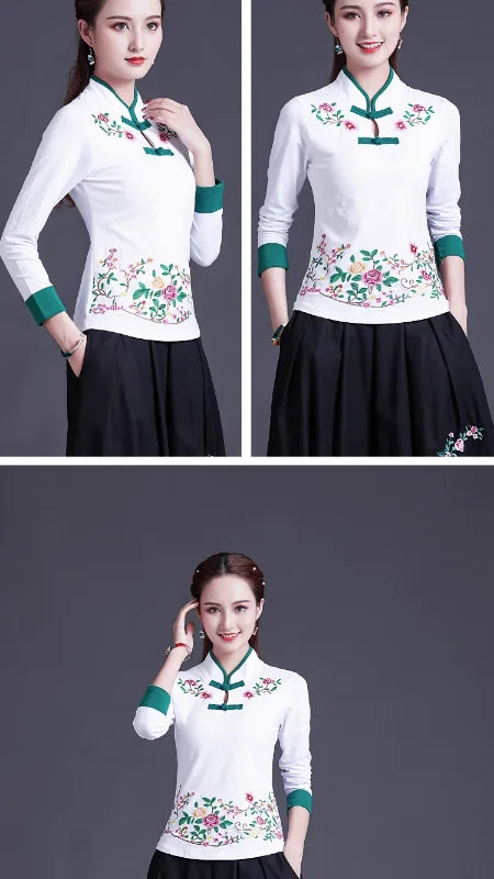 Woman wearing a white blouse with green accents and floral embroidery, posing against a gray background.