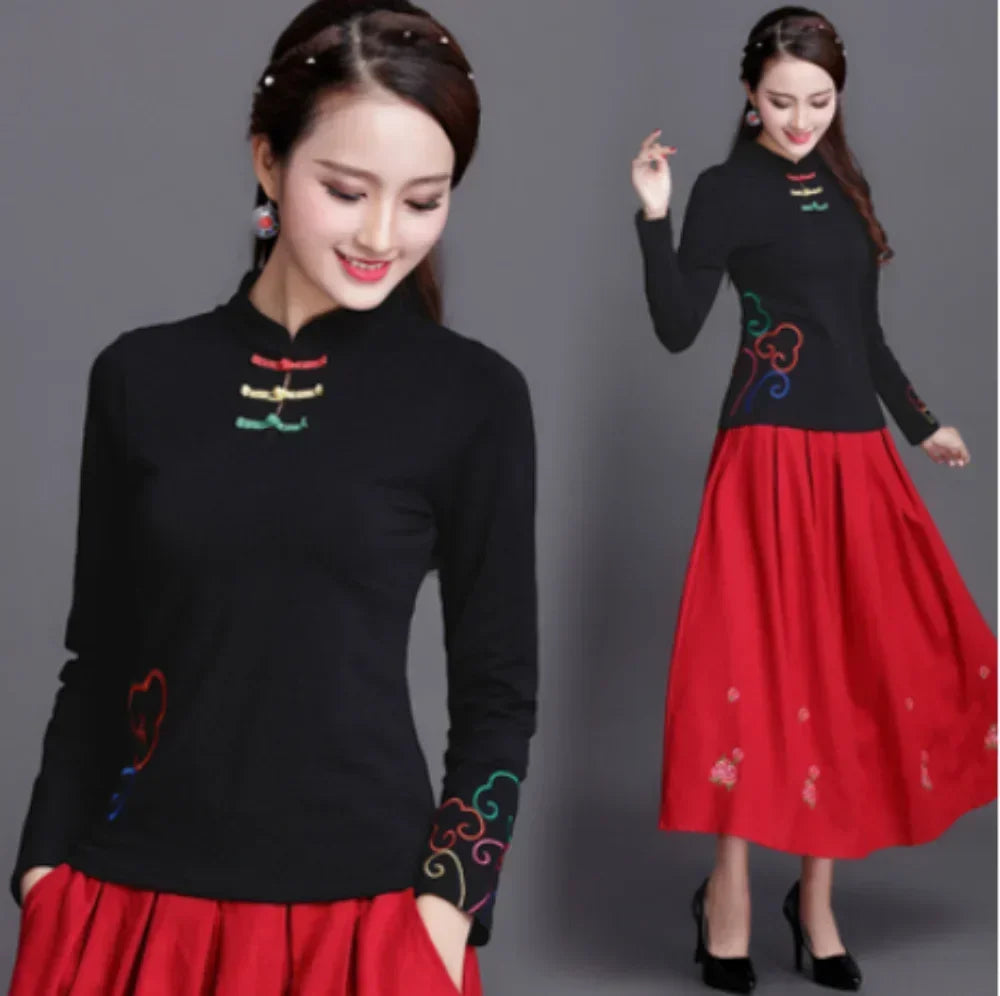 Woman wearing a black top with colorful embroidery and a red skirt on a gray background