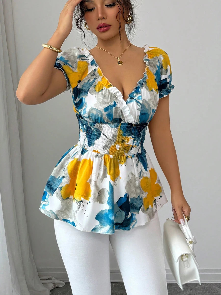 Woman wearing a colorful floral dress with white pants against a neutral background