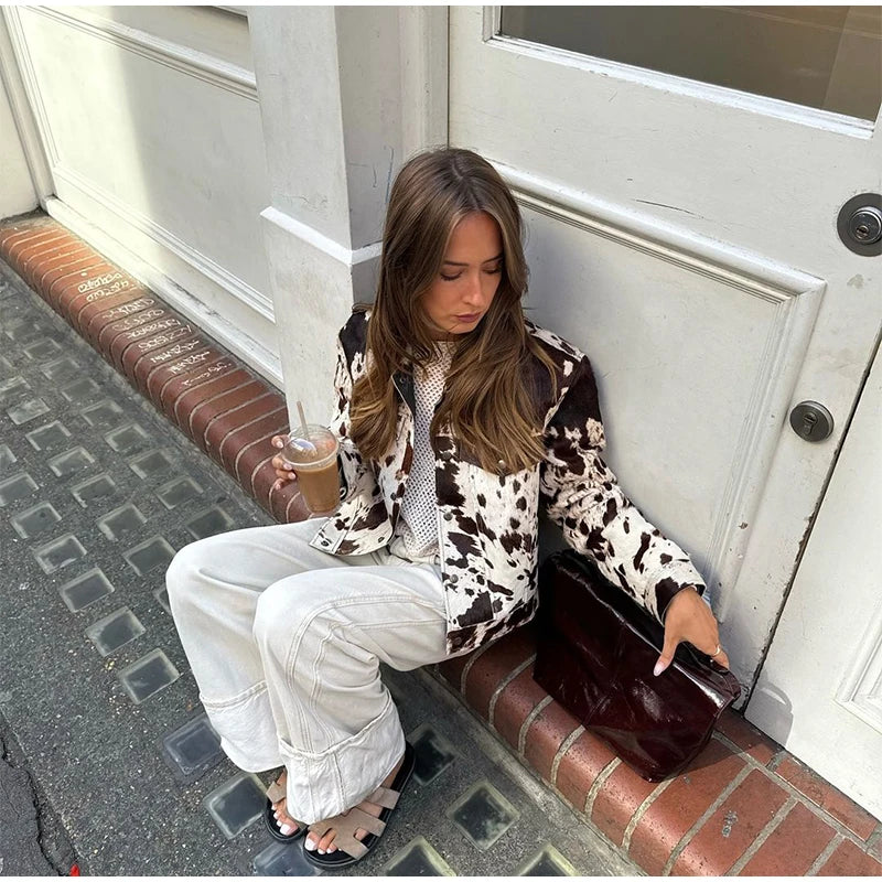 Woman sitting on a step holding a coffee cup and a brown leather clutch.