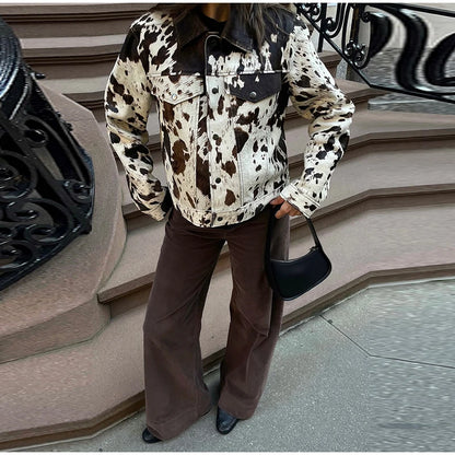 Person wearing a cow print jacket and brown pants standing on steps.