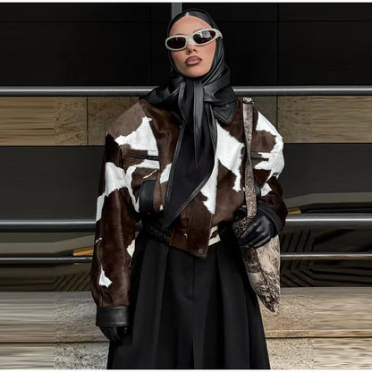 Person wearing a cow print coat with a black outfit and sunglasses in an urban setting