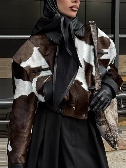 Person wearing a cowhide leather jacket with a dark scarf and gloves in an urban setting.