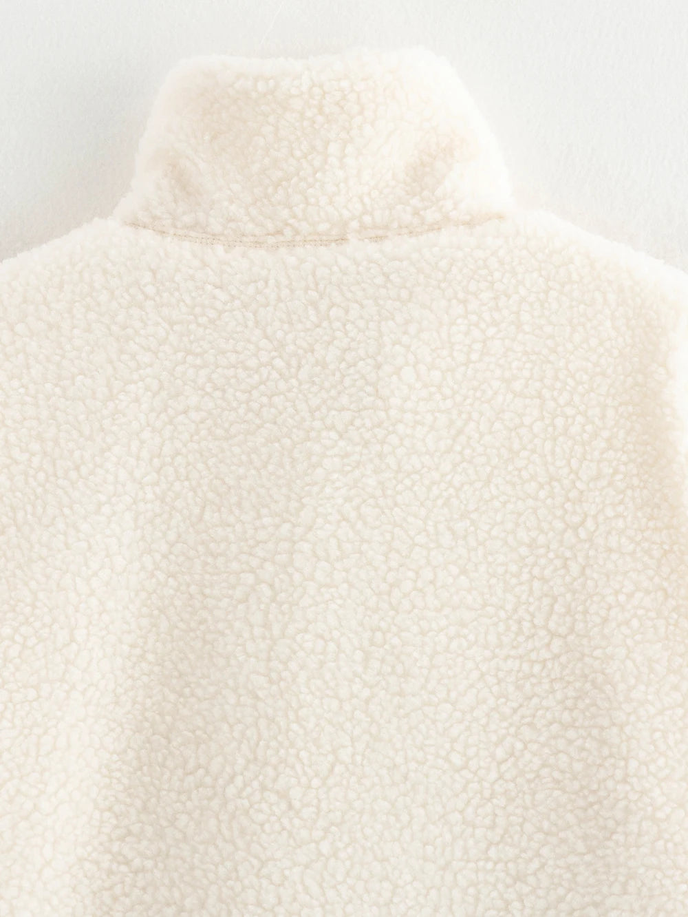 Close-up of a textured white garment on a light gray background