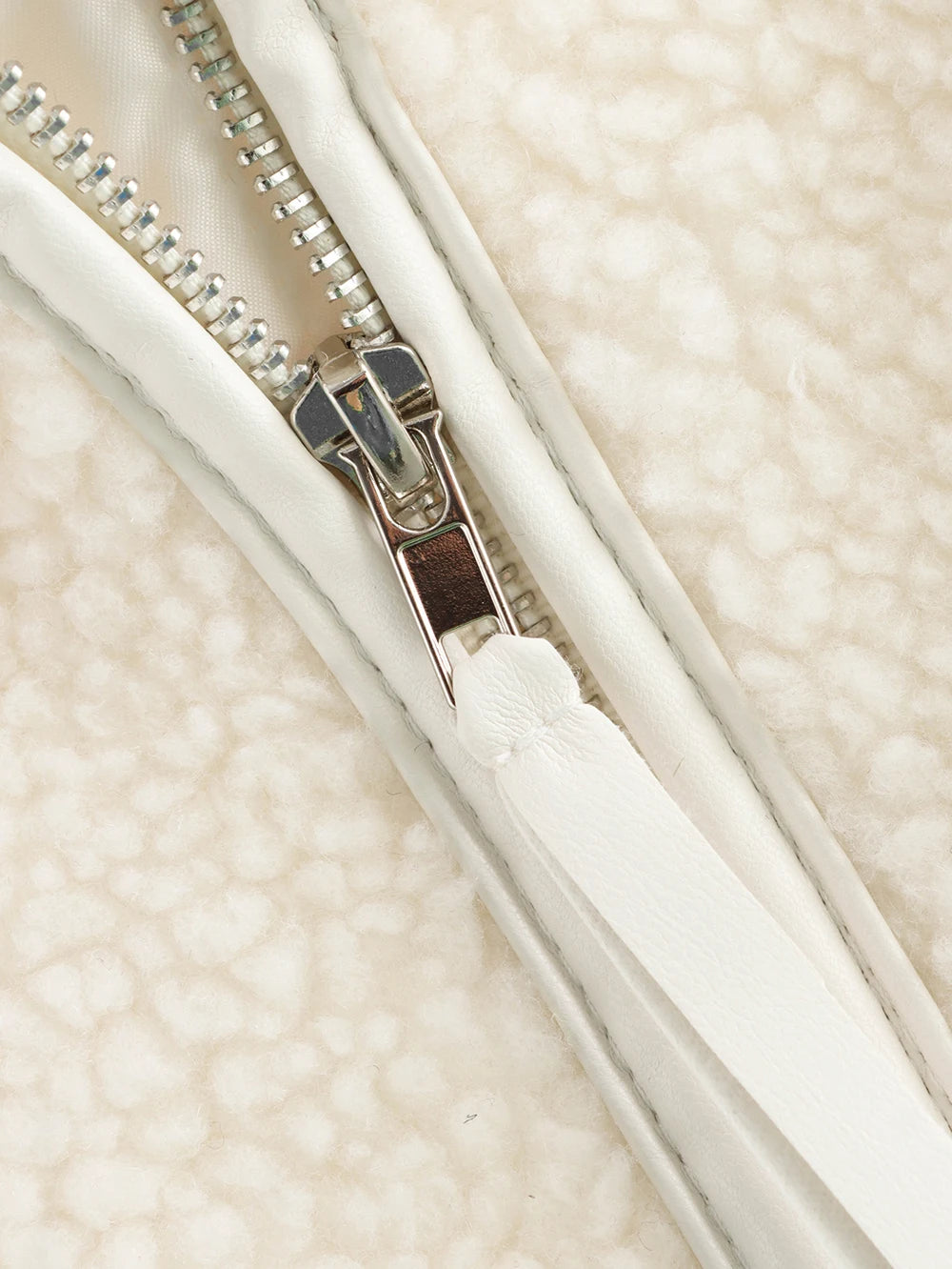 Close-up of a white zipper on a textured beige background