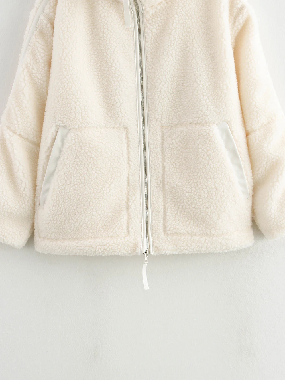 Close-up of a cream-colored fleece jacket on a light gray background