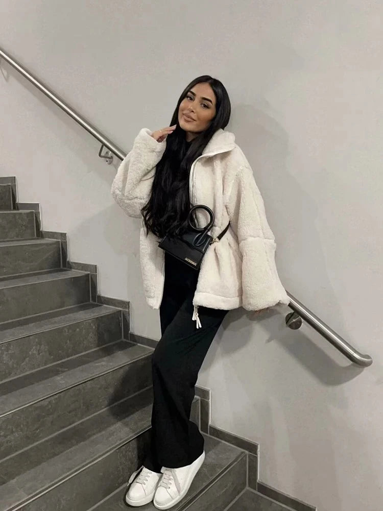 Woman in a white coat standing on a staircase indoors