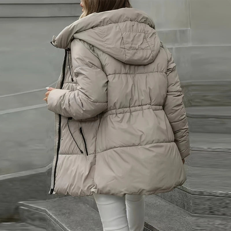 Person wearing a beige puffer jacket on a neutral background