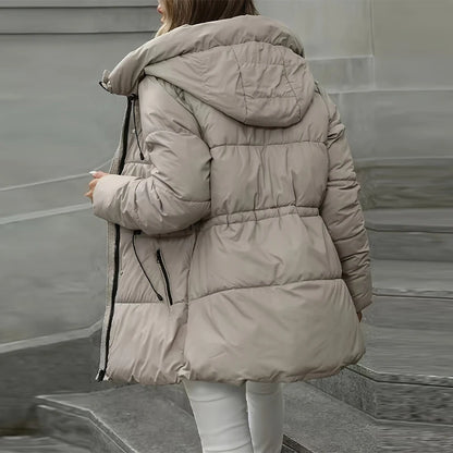Person wearing a beige puffer jacket on a neutral background