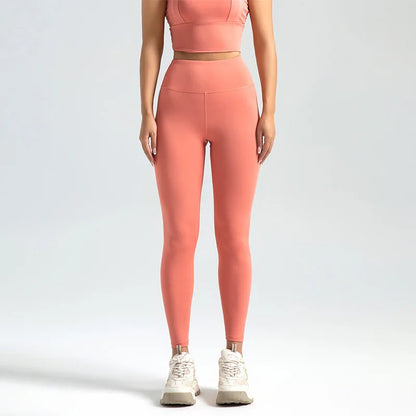 Person wearing coral pink leggings and a matching top on a light gray background