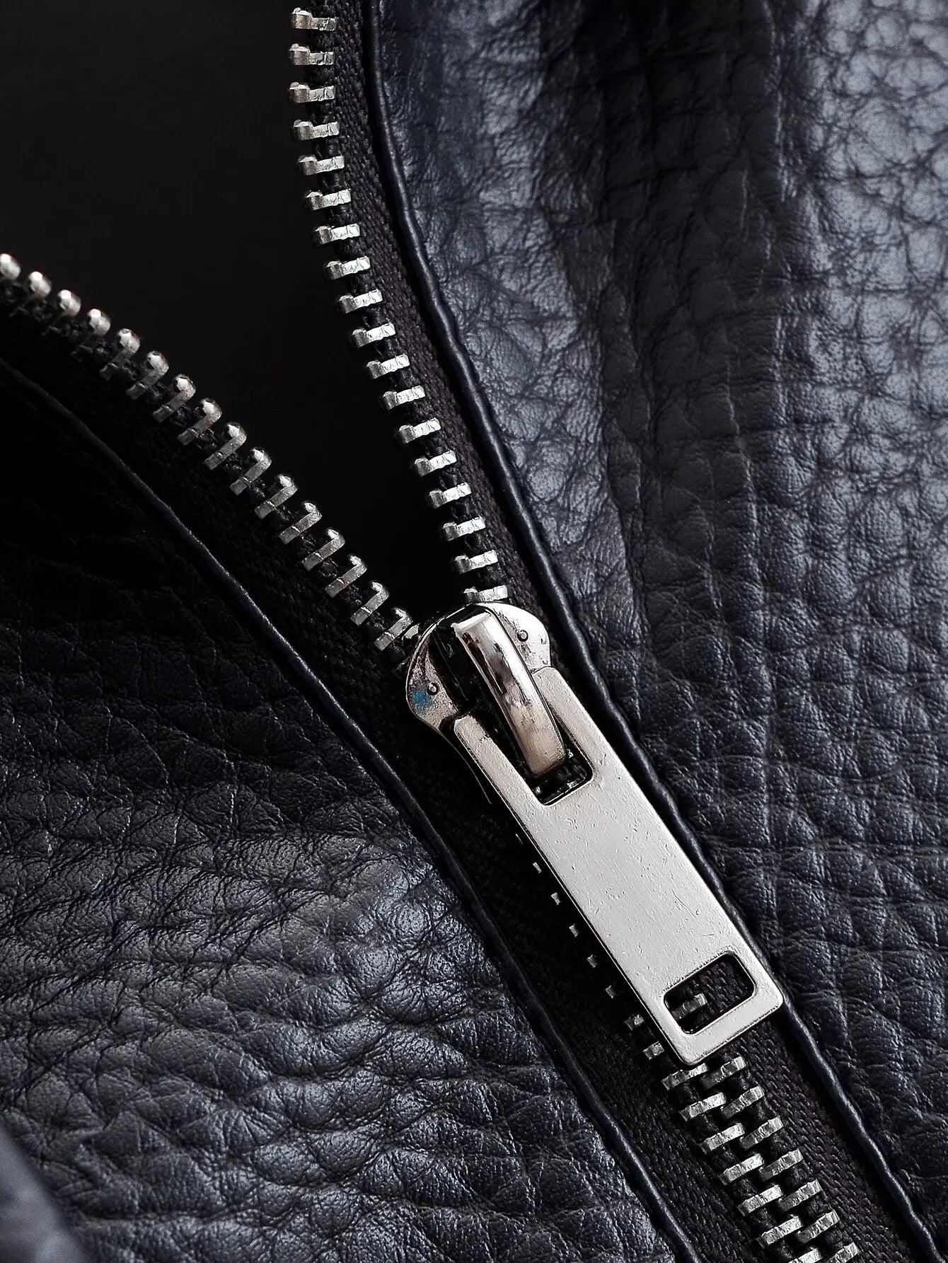Close-up of a black leather jacket with a zipper