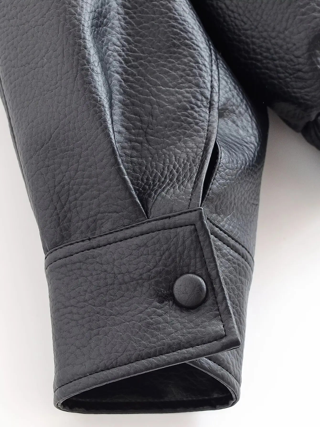 Close-up of a black leather glove with a button on a white background