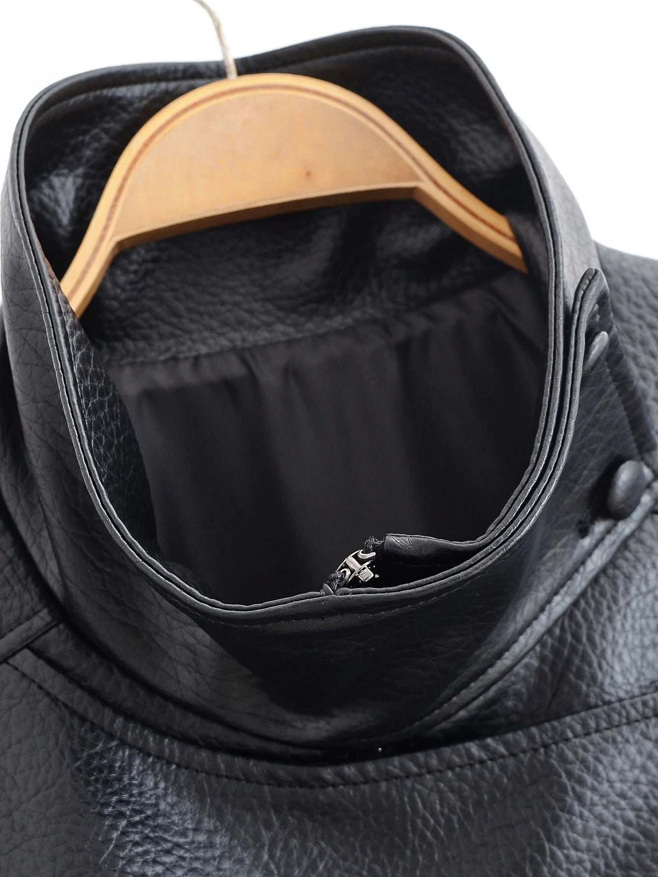 Black leather jacket with a wooden hanger on a white background