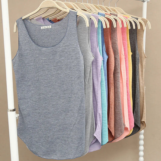 Row of colorful tank tops on hangers against a beige wall.