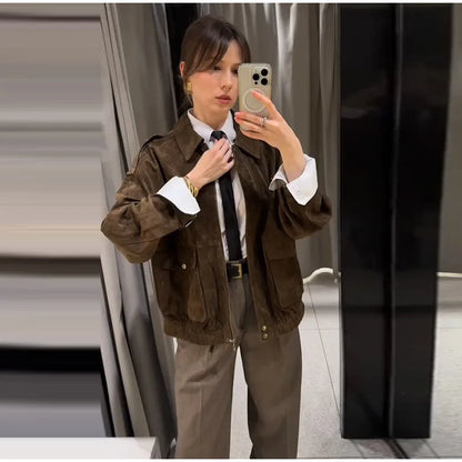 Person taking a mirror selfie wearing a brown jacket and pants in an indoor setting.