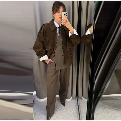 Person wearing a brown trench coat and pants standing in front of a mirror.