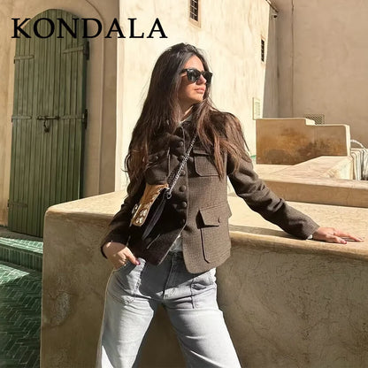 Woman in a brown jacket and sunglasses standing on steps with 'KONDALA' branding.