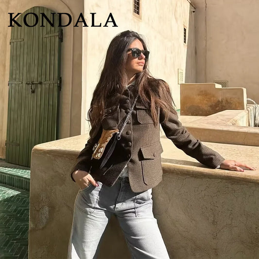 Woman in a brown jacket and sunglasses standing on steps with 'KONDALA' branding.
