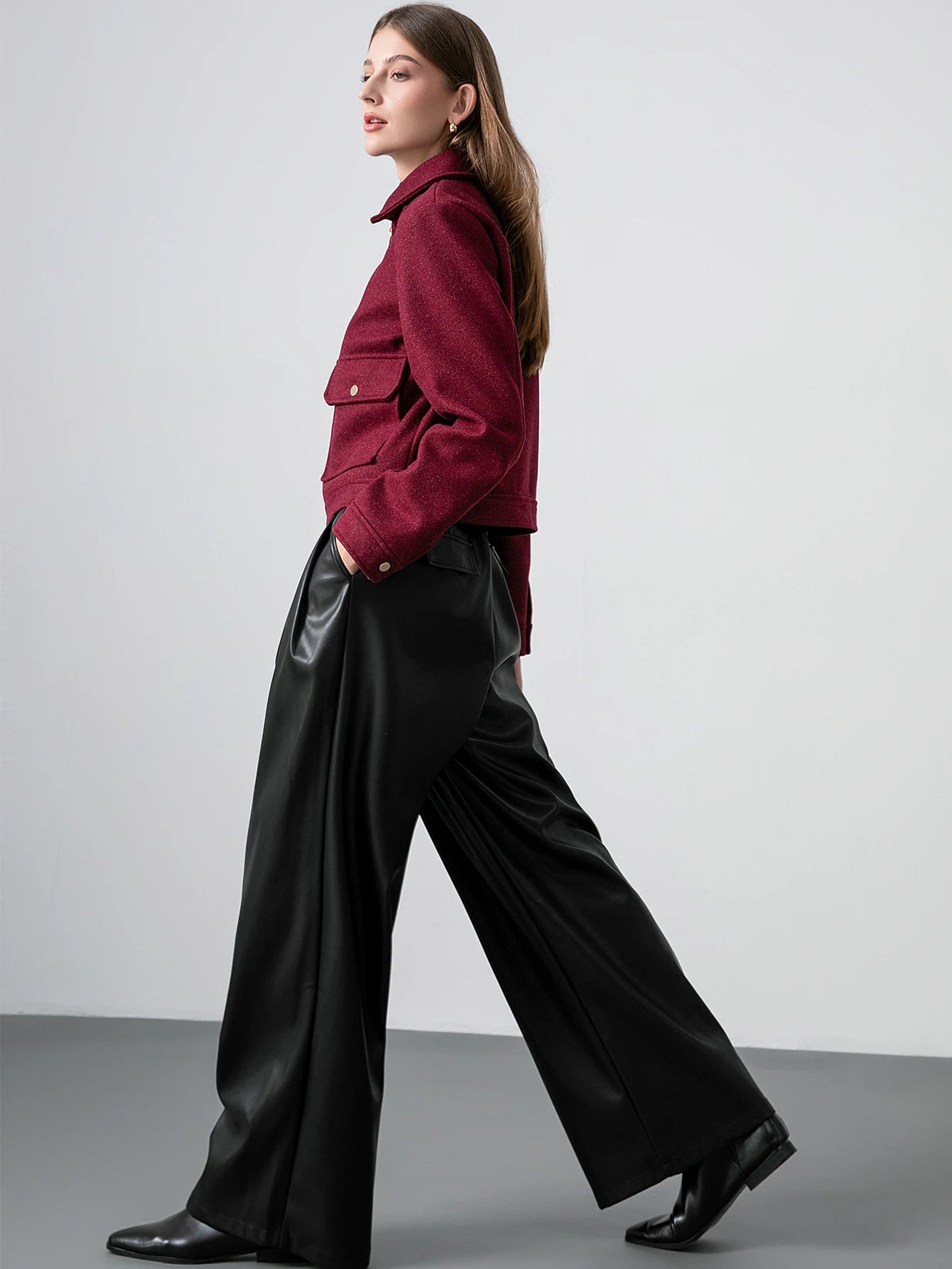 Woman wearing a red jacket and black pants against a plain background