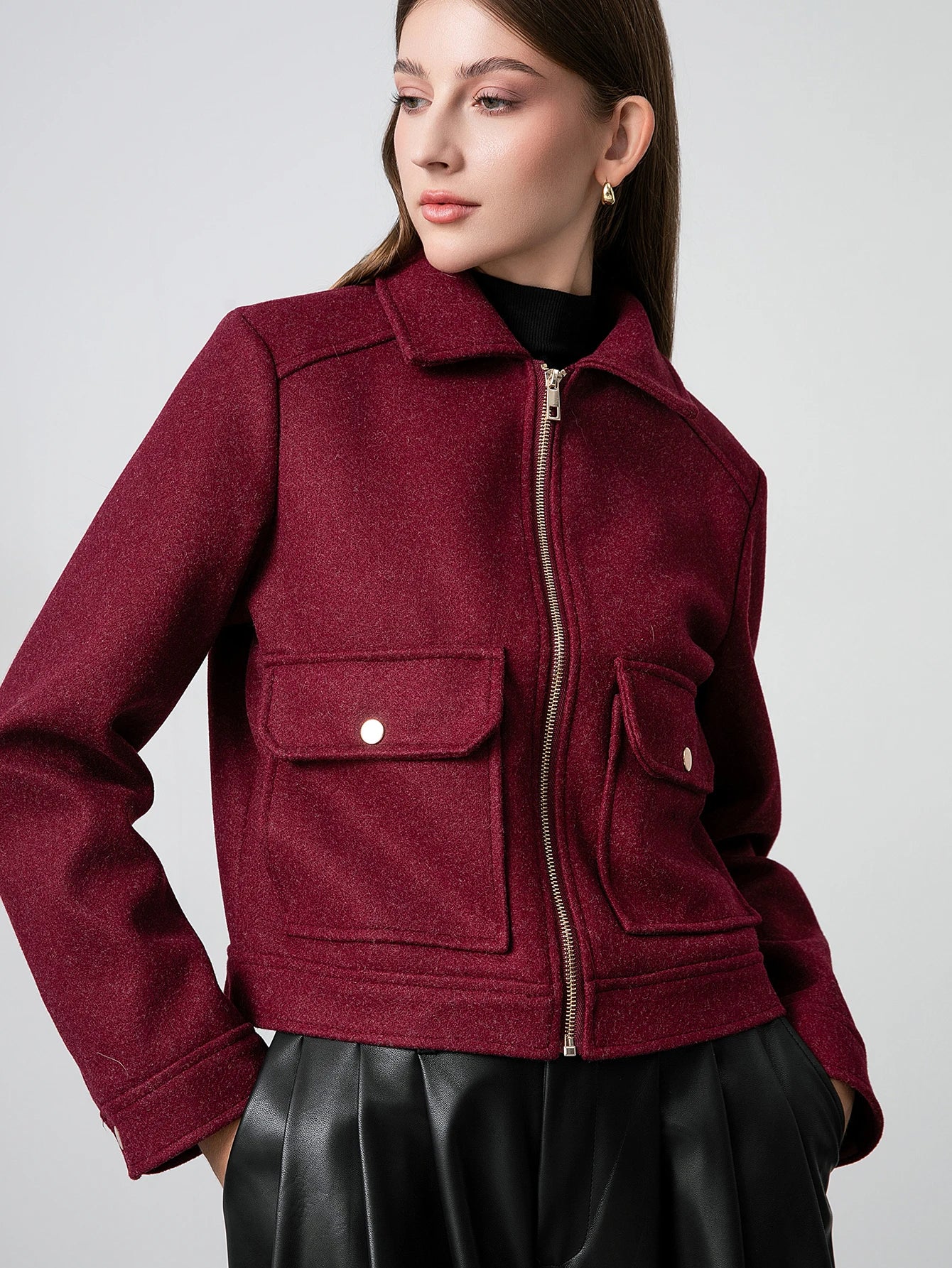 Woman wearing a burgundy jacket with a plain background