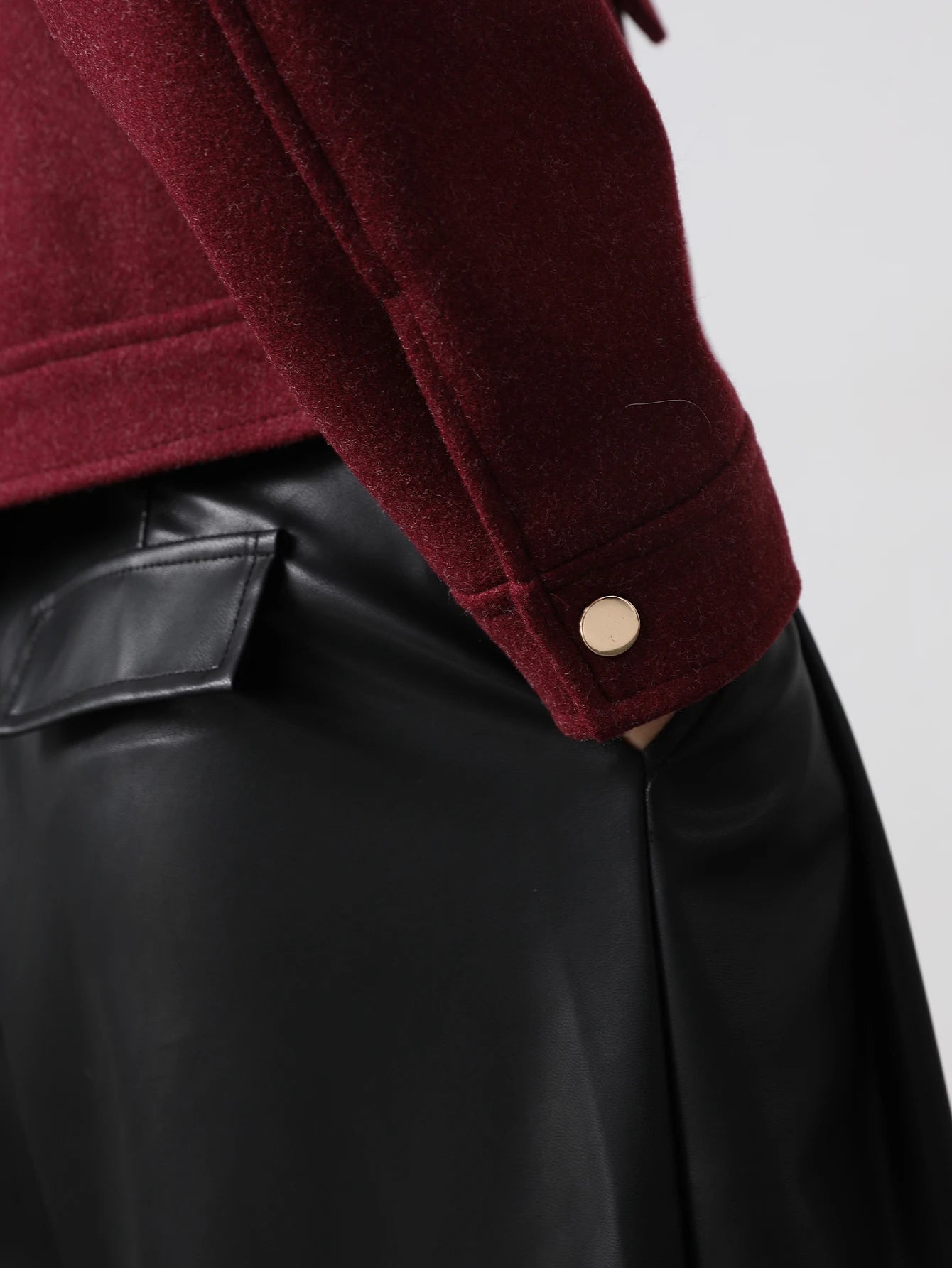 Close-up of a burgundy jacket with a button on a plain background