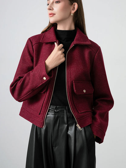 Woman wearing a burgundy jacket with a plain background