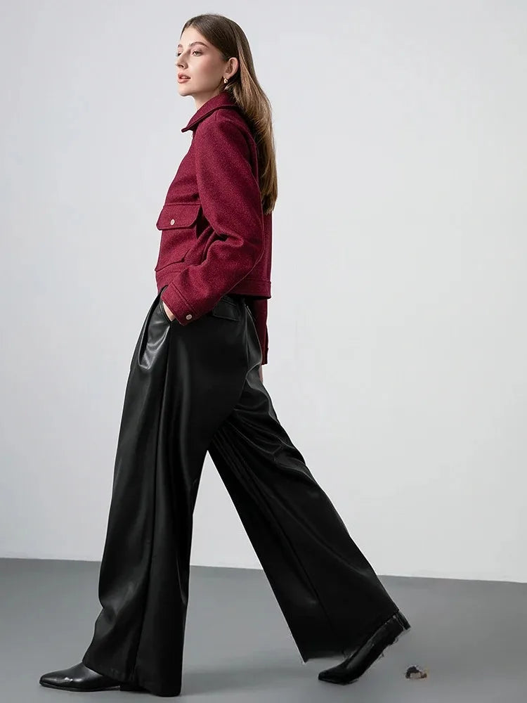 Woman wearing a red jacket and black pants on a plain background