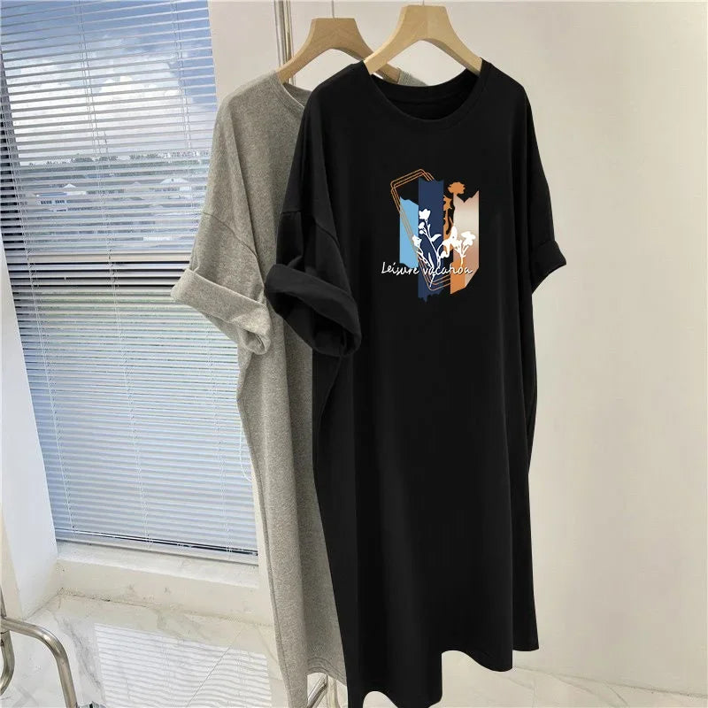 Black t-shirt with graphic design on a hanger in front of a window.