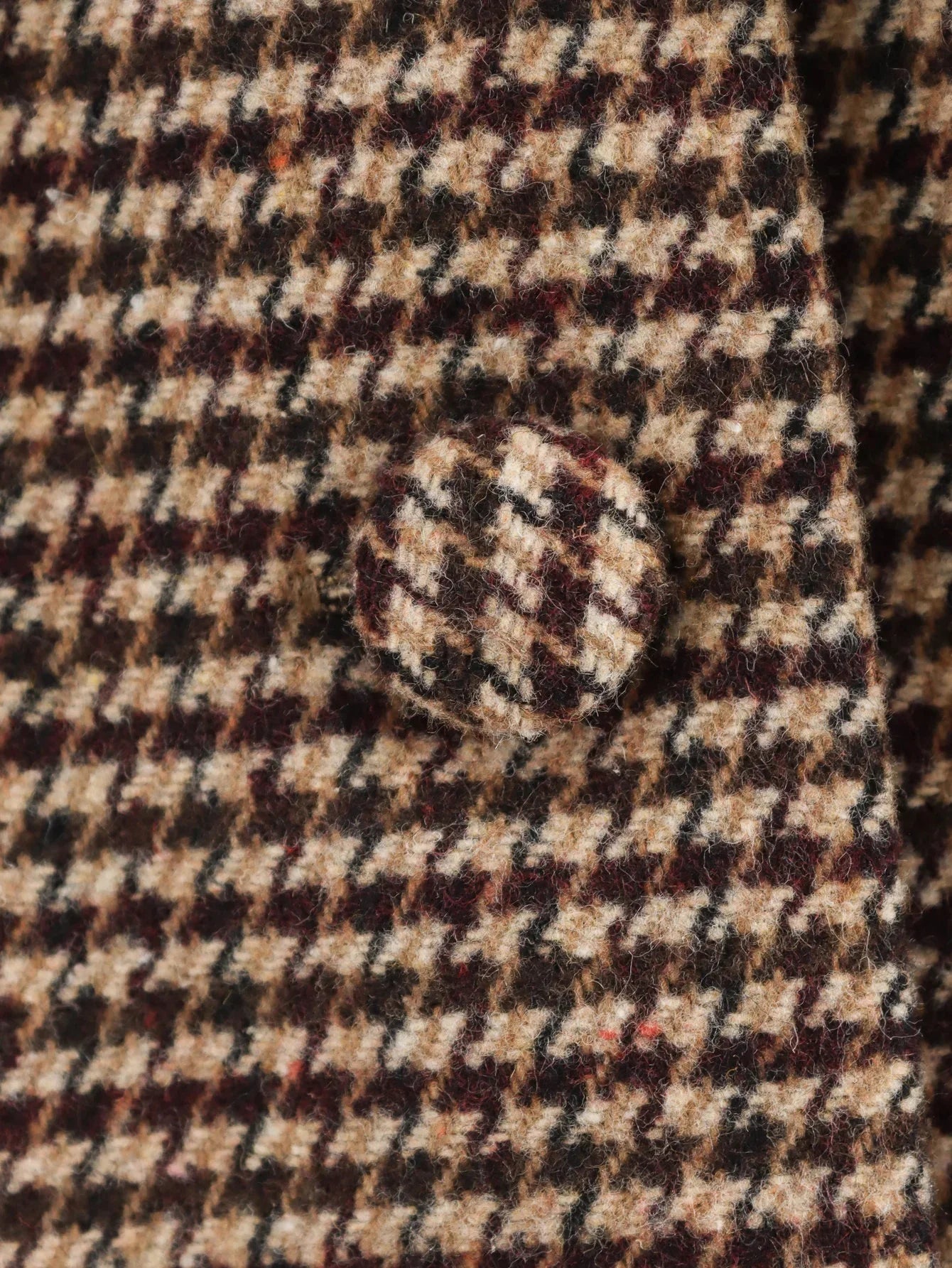 Close-up of a houndstooth patterned fabric with a button.
